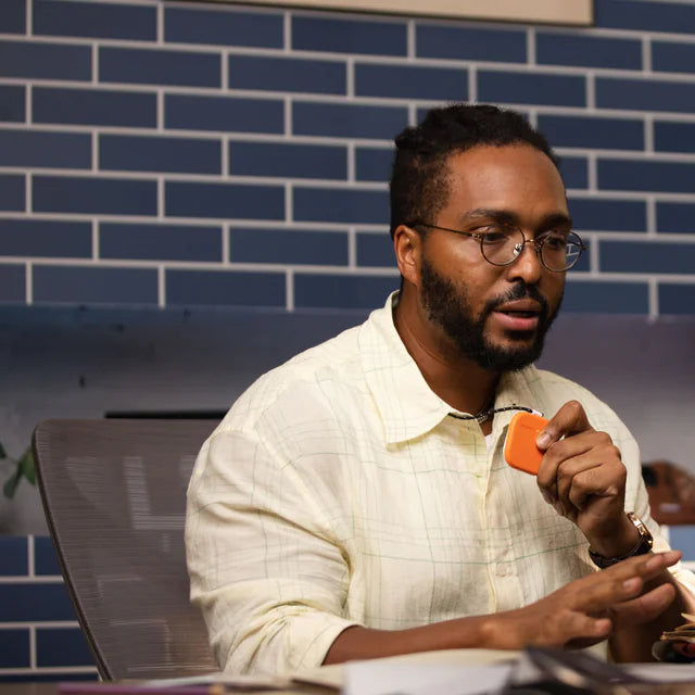 Man holding an orange SpeakON device beside a laptop