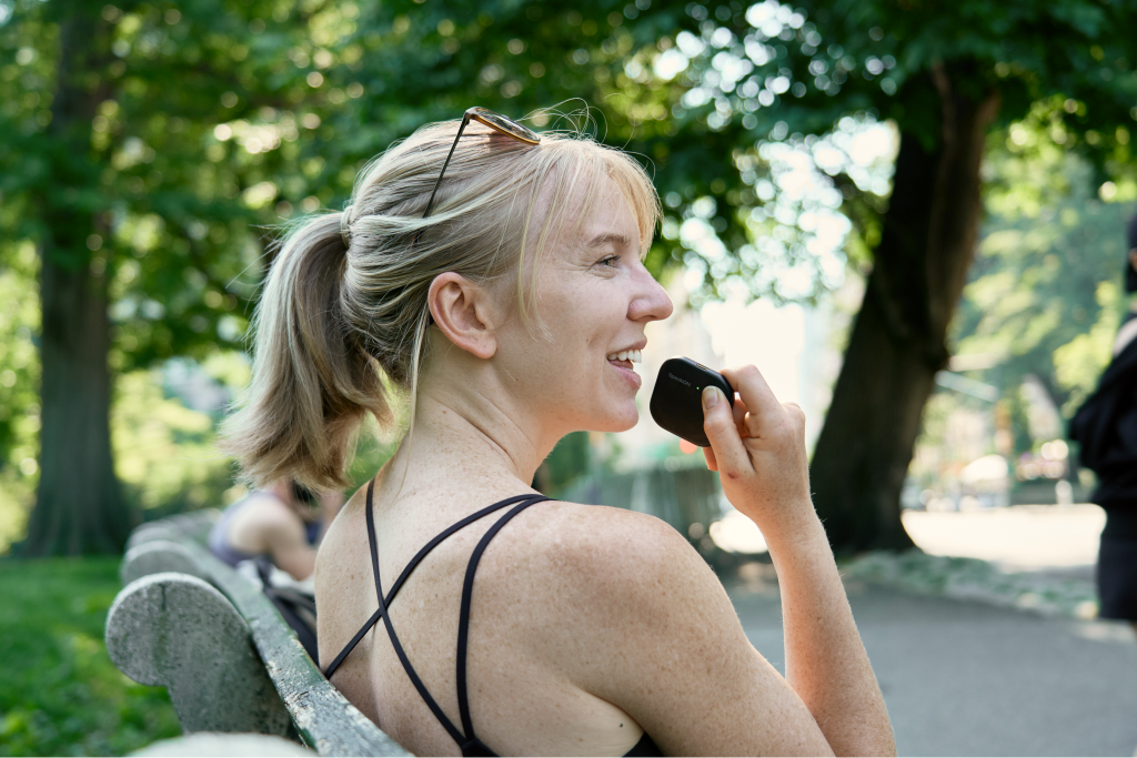 A woman uses SpeakON to edit a first draft outdoors.